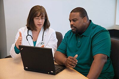 Photo of doctor with patient looking at computer