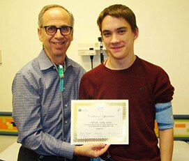 Photo of Dr. Bradley Warady and Malachi Gerke holding certificate marking their tenth year of participation in Chronic Kidney Disease in Children study