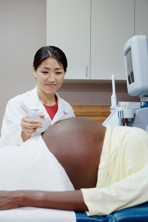 A female ultrasound technician performing an ultrasound on a pregnant woman