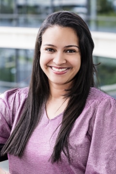 Female with brown hair smiling and wearing a pink shirt.