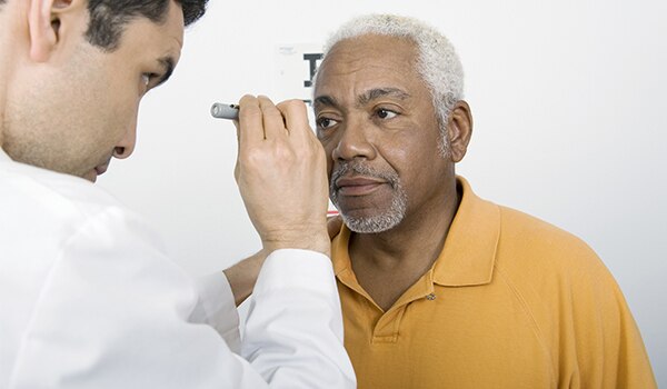 Male doctor giving male patient eye exam