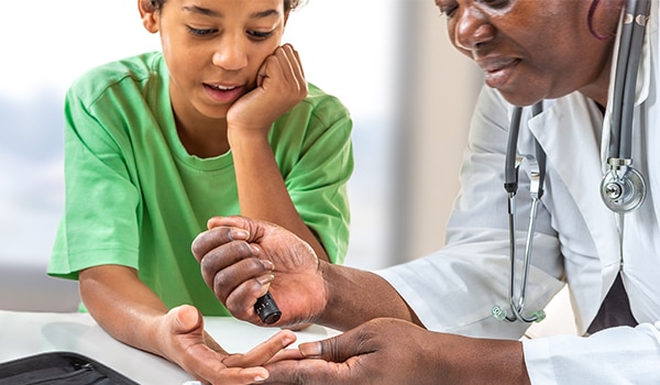 A doctor showing a child how to check their blood sugar.