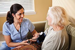 A nurse takes the blood pressure of an elderly lady