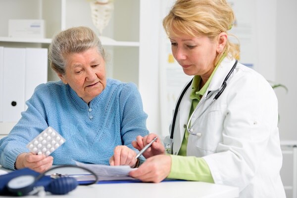 Photo of an older woman talking with her doctor. They are looking at a piece of paper.
