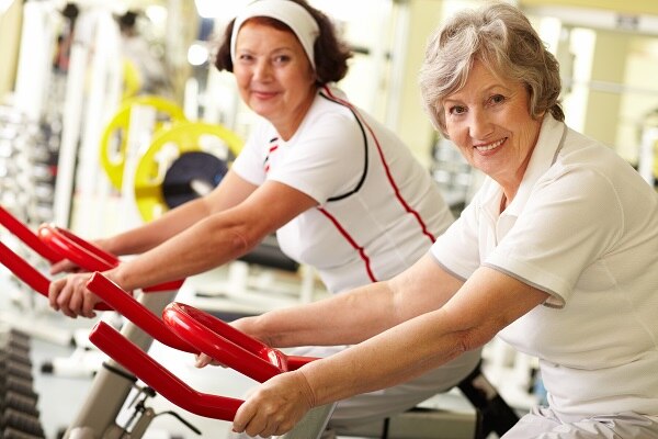 Photo of two smiling middle-aged women on exercise bikes