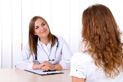 A female doctor sitting at a desk talking with a female patient.