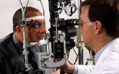 Eye doctor examines a man's eyes for signs of eye disease during a full, yearly eye exam.