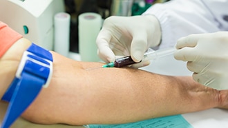 A health care professional draws blood from a person’s arm.