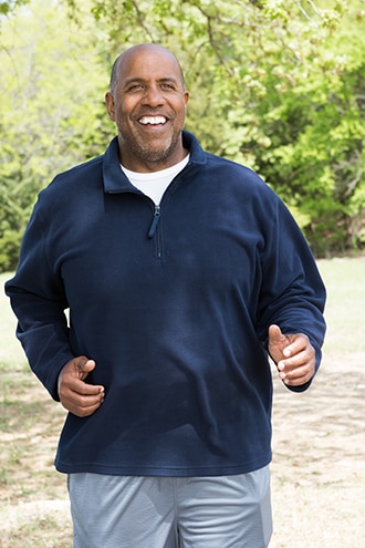 An African American man walking briskly in a park