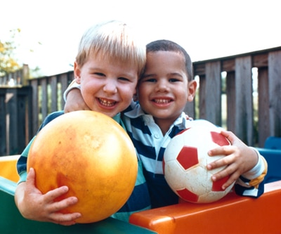 Dos niños sostienen pelotas de goma y sonríen a la cámara.