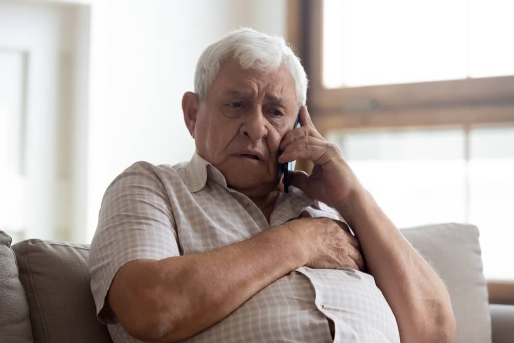 Hombre mayor con cara de preocupación hacienda una llamada telefónica.