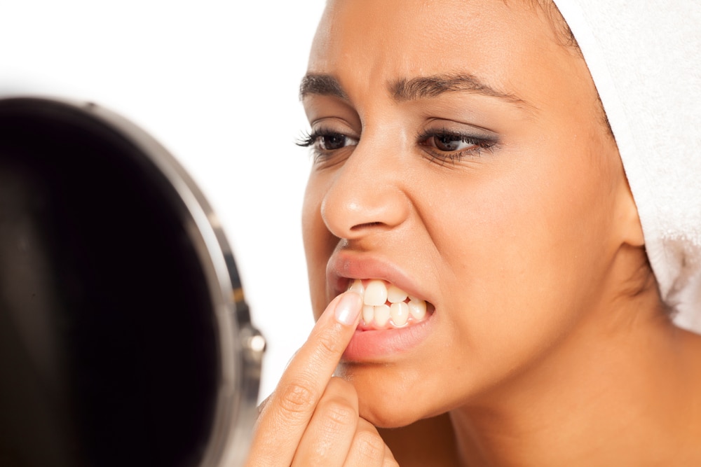 Una mujer se revisa los dientes en un espejo.