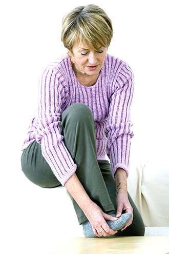 Una mujer masajeándose el pie.