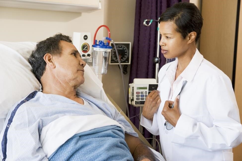 Profesionales de atención médica hablando con un paciente en una cama de hospital