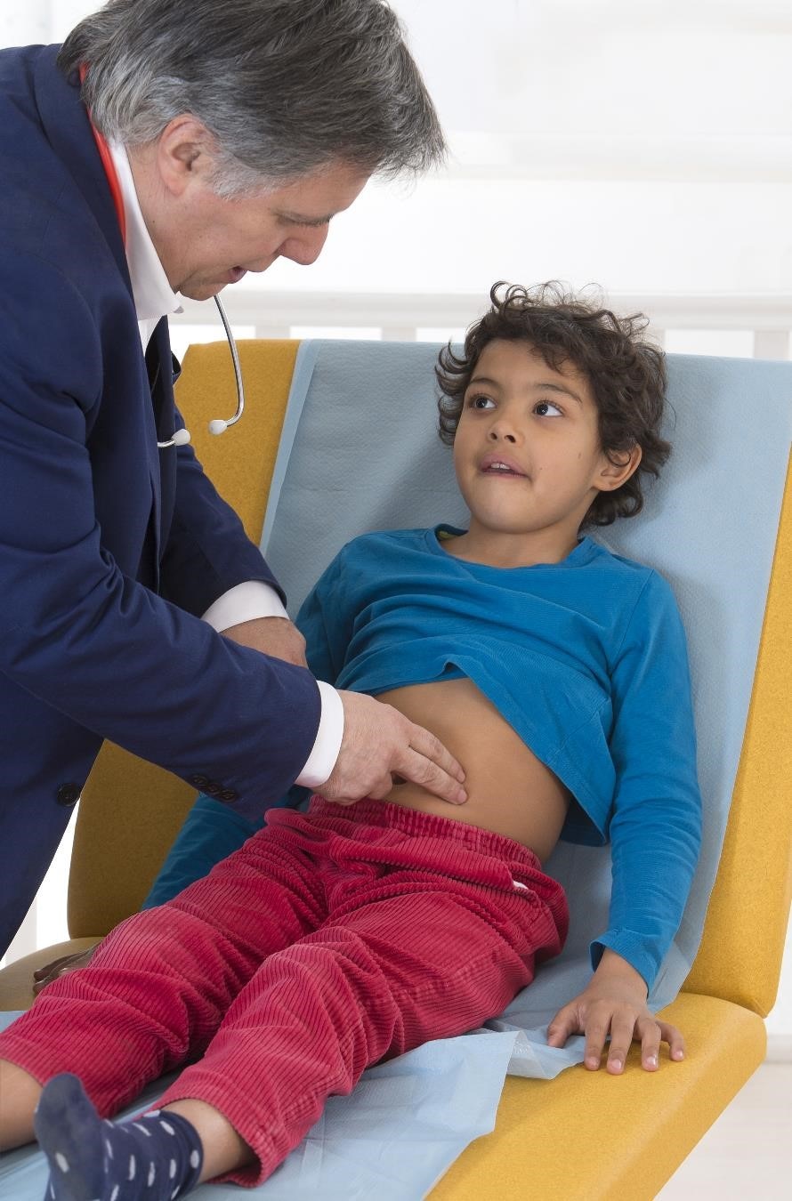 Médico examinando el abdomen de un niño durante el examen físico