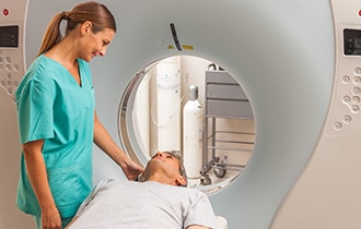 A health care professional speaking to a patient before he enters a magnetic resonance imaging (MRI) machine.