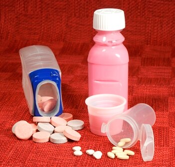 Various antacids are shown in this picture without any brand names (left to right): chewable tablets, pink liquid, and ingestible pills.