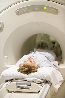 Una mujer entrando a una máquina de tomografía computarizada.