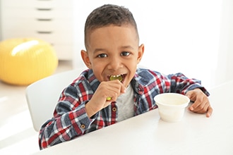 Un niño pequeño comiendo yogur.