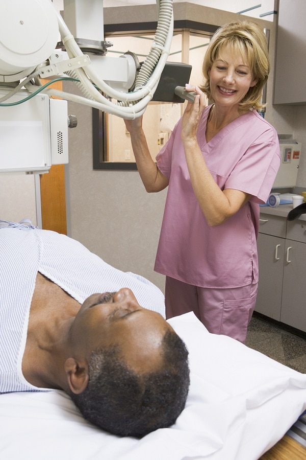 Técnica instalando la máquina para la radiografía y el paciente acostado en la camilla.
