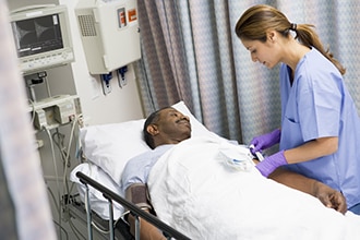 Un hombre acostado en una cama de hospital se prepara para la cirugía con una profesional de atención médica.