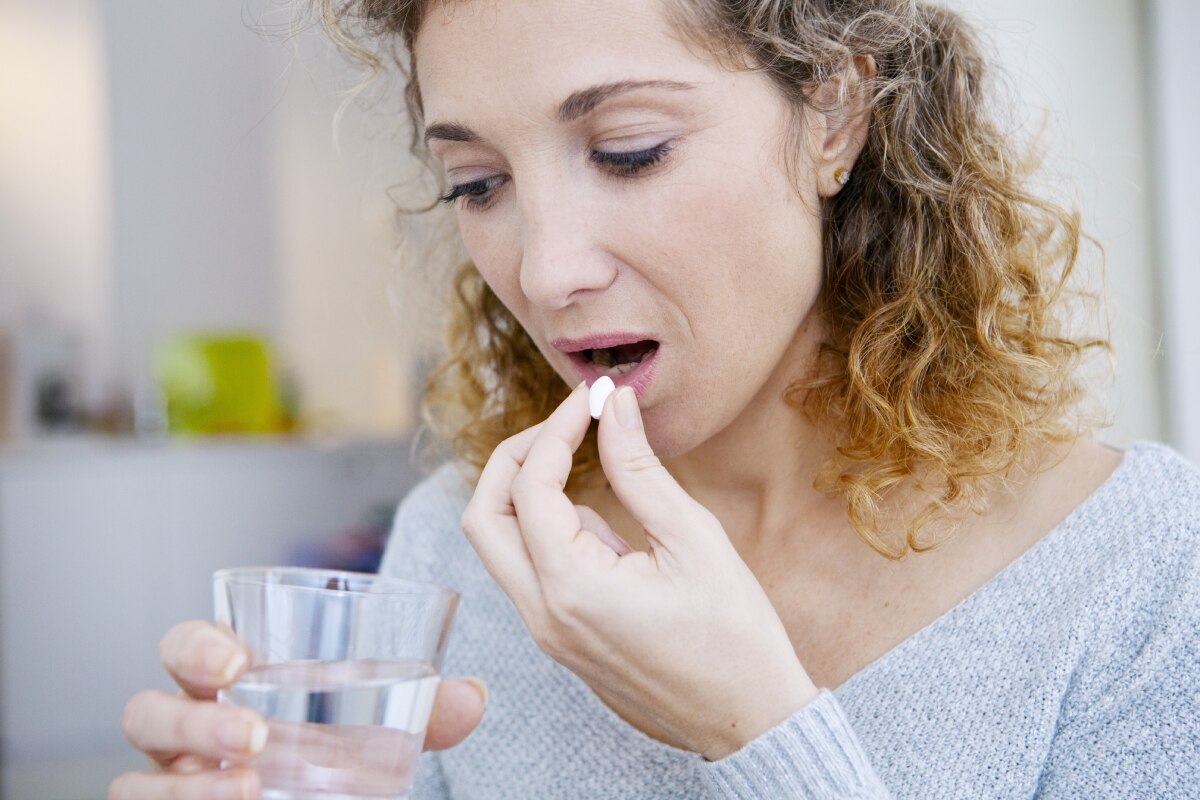 A woman taking a pill.