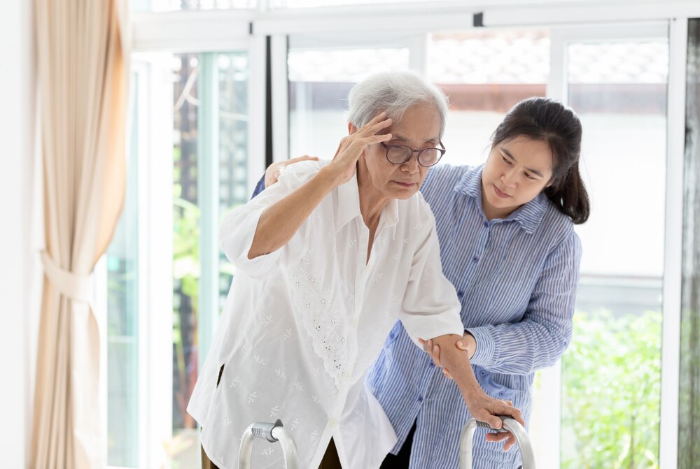 A young woman supports an older woman who appears to be dizzy.