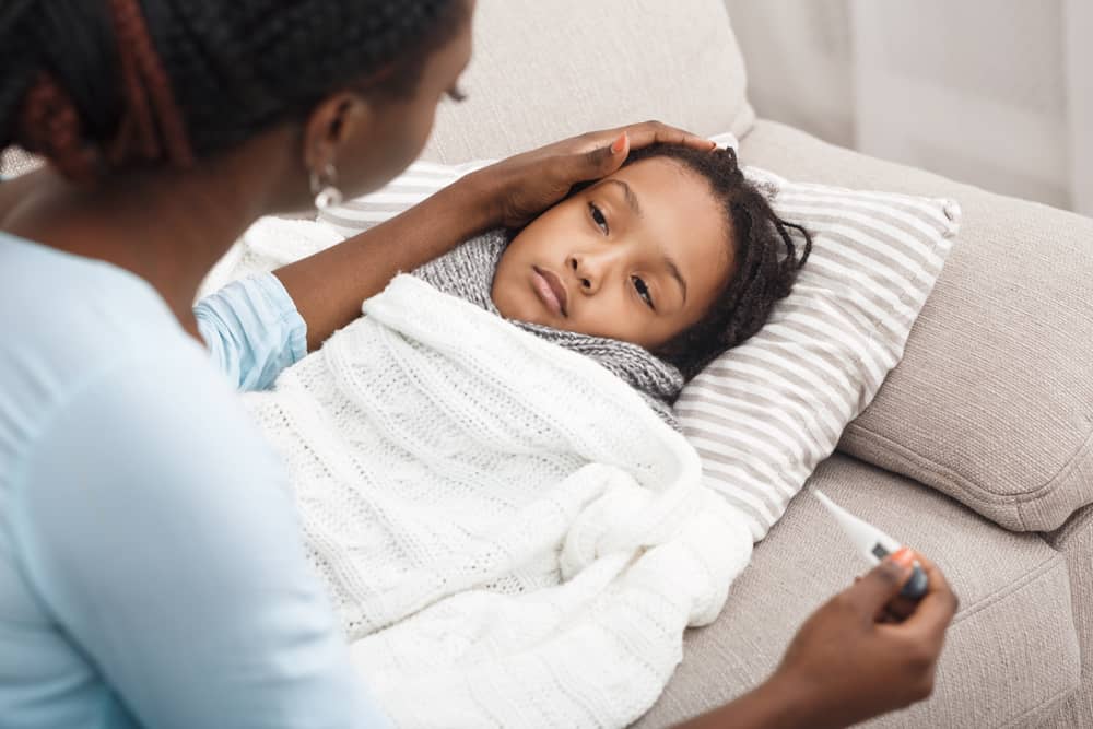 Alt-text: A mother checks her child’s temperature with a digital thermometer.