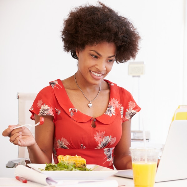 Woman eating a small snack at her desk.