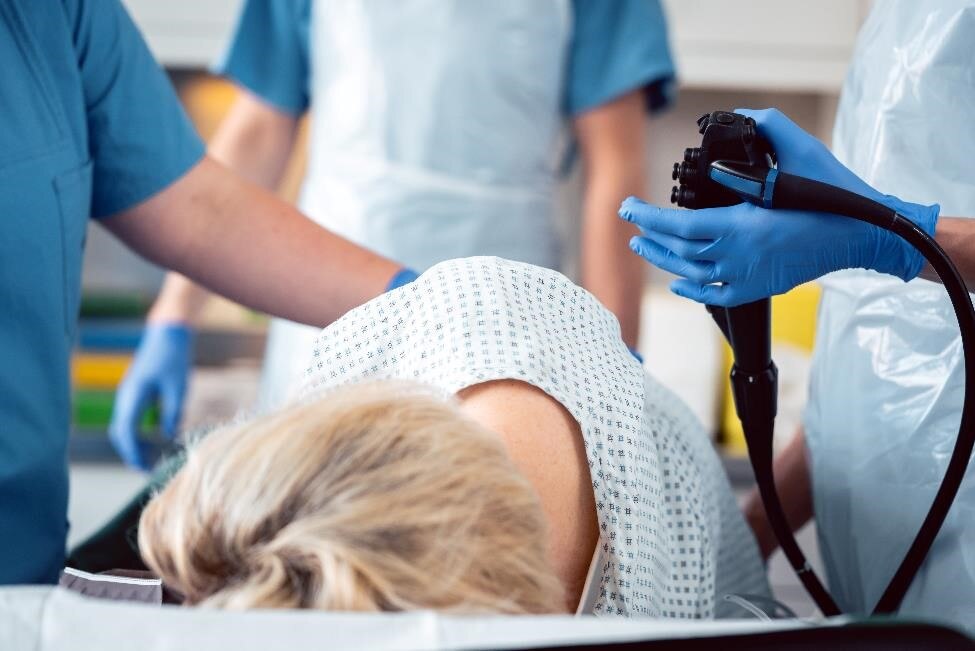 Patient lying on her side while health care professionals perform an endoscopy test.