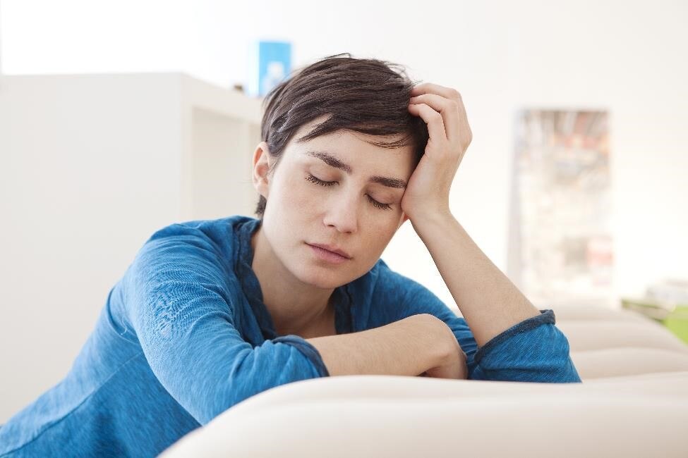 A woman with her eyes closed, resting her head on her palm.