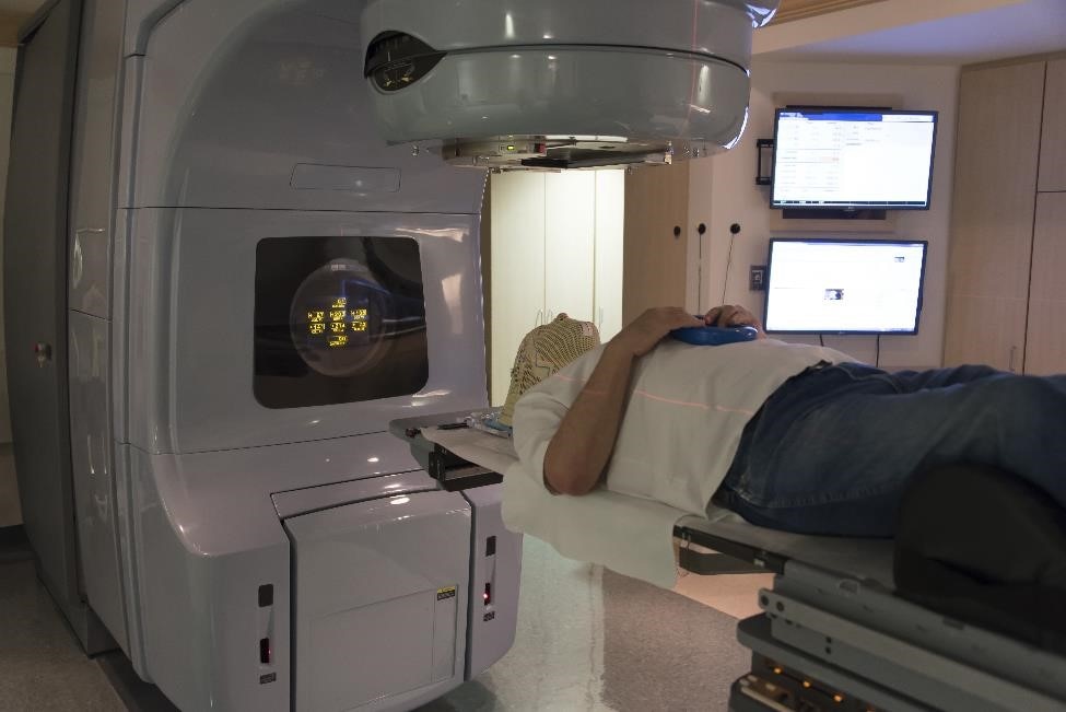 A male patient lies in a radiation therapy machine that aims radiation beams at the pituitary tumor.