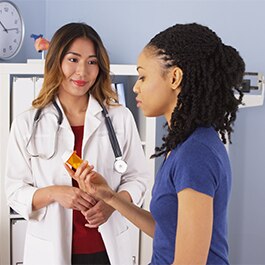 doctor holding pill and talking to a patient