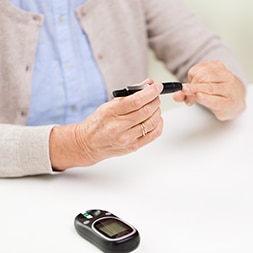 senior woman with glucometer checking blood sugar level at home