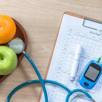 Diabetes monitor, fruit, and clipboard