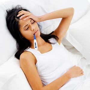ill woman taking her temperature in bed wile feeling sick