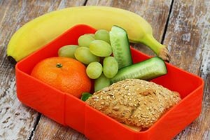 Alimentos ricos en fibra , incluyendo un plátano , una naranja , uva , pepino , y un sándwich con pan integral