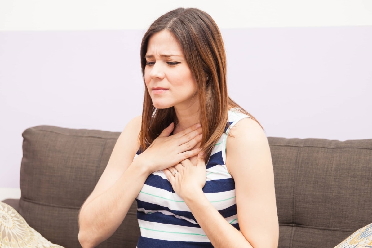 A woman experiencing heartburn and pressing a hand to her chest.