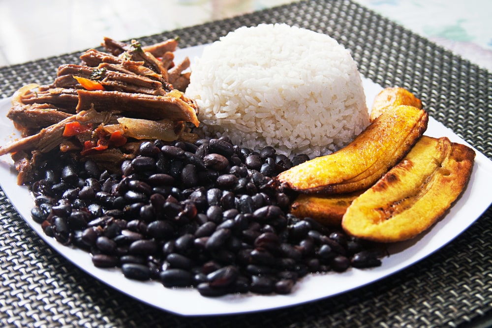  A plate of rice, shredded beef, stewed black beans, and plantains.