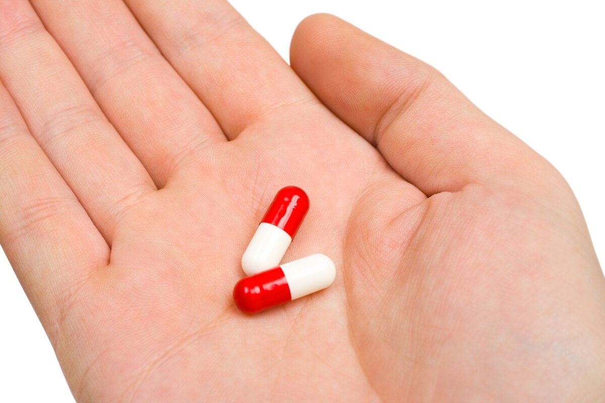 Una mano abierta sostiene dos cápsulas de medicamento.