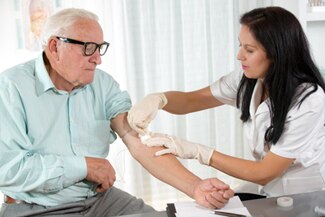 Foto de una enfermera extrayendo sangre de un anciano en el consultorio de un médico.