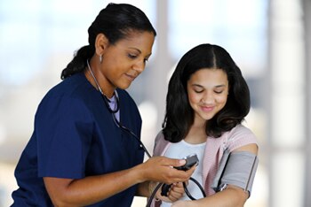 A health care professional checking a patient’s blood pressure.