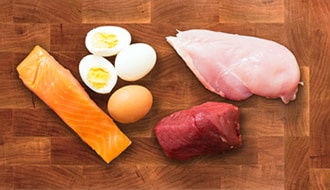 Un pedazo  de salmón, huevos, un filete de pollo y un pedazo de carne roja.