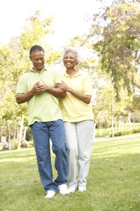 A photo of an older man and woman walking in a park.