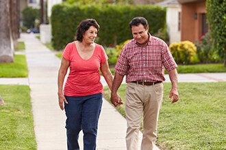 Smiling couple walking on the sidewalk holding hands.