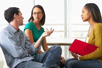 A photo of a man and a woman speaking with a genetics counselor.