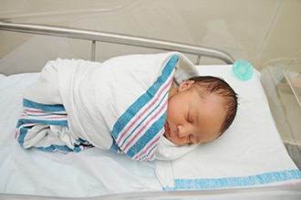 A newborn baby in a hospital crib