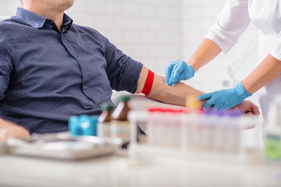 Health care professional preparing to take a blood sample from a patient.