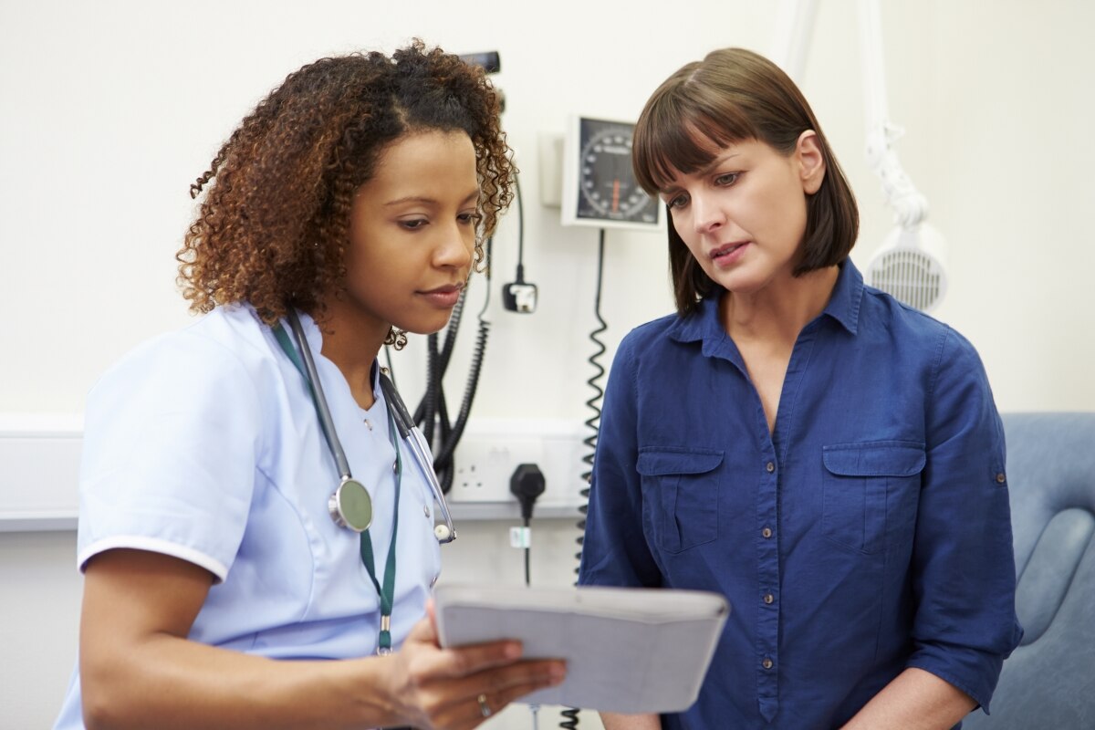 A health care professional talking with a patient who is a woman.
