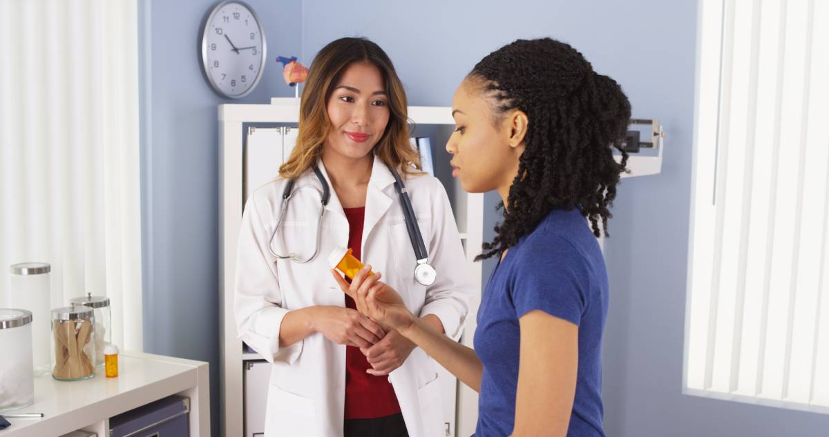 Doctor talking with a patient who is holding a medicine bottle.